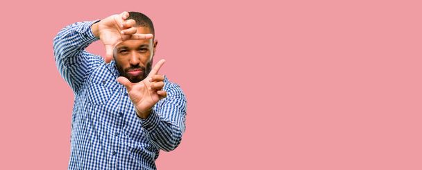 Uomo afroamericano con la barba fiducioso e felice mostrando le mani alla macchina fotografica, comporre e inquadrare gesto
 - Foto, immagini