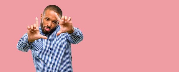 Hombre afroamericano con barba confiada y feliz mostrando las manos a la cámara, componiendo y enmarcando gesto
 - Foto, Imagen