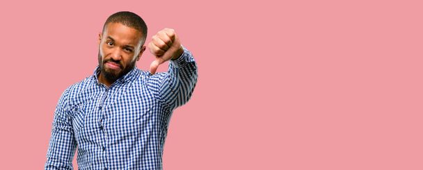 Africano americano com barba mostrando polegares para baixo sinal infeliz de aversão, expressão negativa e desaprovação
 - Foto, Imagem