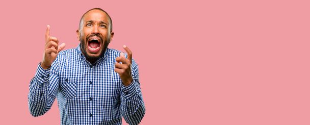 Hombre afroamericano con barba aterrorizada y nerviosa expresando ansiedad y gesto de pánico, abrumada
 - Foto, imagen