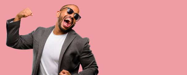 Hombre afroamericano con barba feliz y emocionado celebrando la victoria expresando gran éxito, poder, energía y emociones positivas. Celebra el nuevo trabajo alegre
 - Foto, imagen