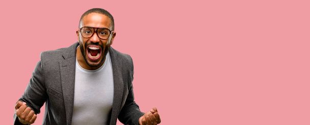 Homme afro-américain avec barbe heureux et excité célébrant la victoire exprimant grand succès, puissance, énergie et émotions positives. Célébre nouveau travail joyeux
 - Photo, image