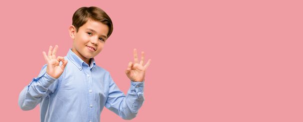 Beau tout-petit enfant avec les yeux verts faisant signe ok geste avec les deux mains exprimant la méditation et la relaxation
 - Photo, image