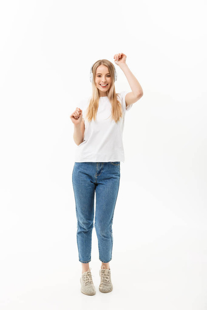 Lifestyle Concept: Portrait of a cheerful happy girl student listening to music with headphones while dancing isolated over white background - Foto, Imagen