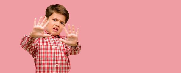Красавчик ребенок с зелеными глазами отвращение и злость, держа руки в стоп жест, в качестве защиты, кричать
 - Фото, изображение