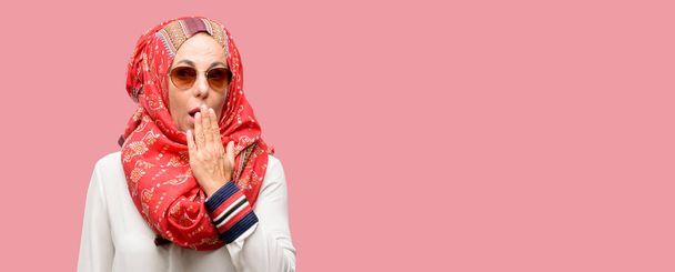 Średnim wieku Emiraty Muzułmanka noszenie hidżabu obejmuje usta w szoku, wygląda nieśmiały, wyrażając ciszy i błąd pojęcia, przestraszony - Zdjęcie, obraz