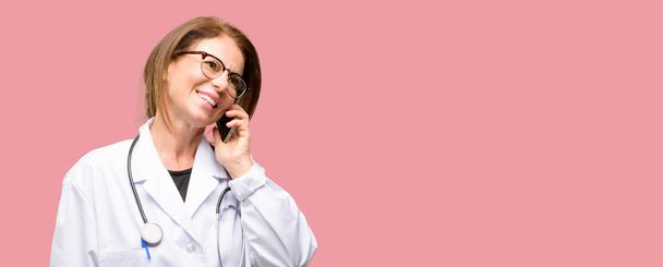 Médico mujer, profesional médico feliz hablando con un teléfono móvil smartphone
 - Foto, imagen
