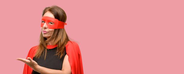 A középkorú szuper hős nő visel piros maszk és a cape gazdaság valami üres kézzel - Fotó, kép