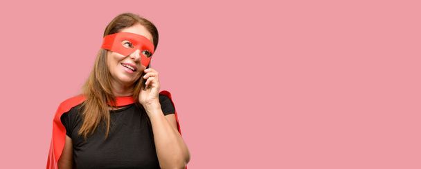 Жінка-супергерой середнього віку в червоній масці та накидку щаслива розмова за допомогою смартфона мобільного телефону
 - Фото, зображення