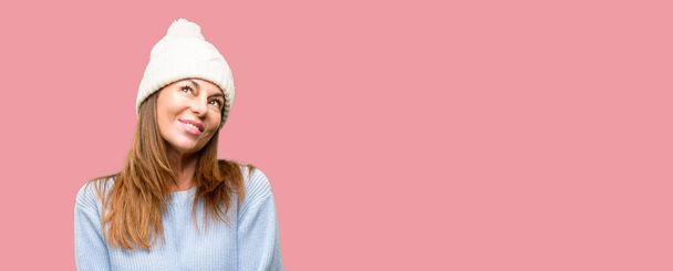 Středního věku žena nosí vlněné zimní čepice myšlení a vzhlédl, vyjádření pochybností a zázrak - Fotografie, Obrázek