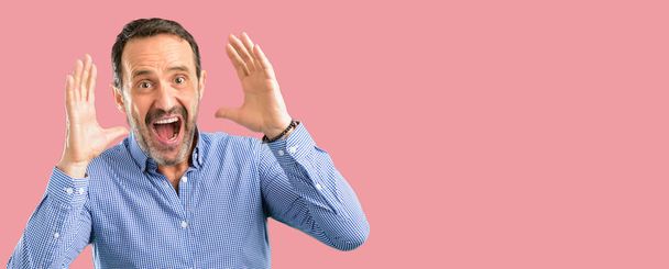 Knappe middelbare leeftijd man blij en verrast juichen waarin wow gebaar - Foto, afbeelding
