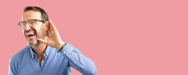 Komea keski-ikäinen mies kädestä lähellä korvaa yrittää kuunnella mielenkiintoisia uutisia ilmaista viestintä käsite ja juoruja
 - Valokuva, kuva
