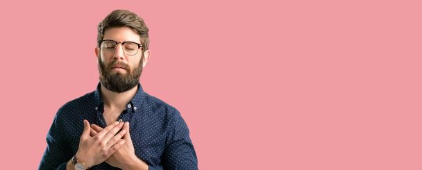 Young hipster man with big beard with hands in heart, expressing love and health concept - Photo, Image