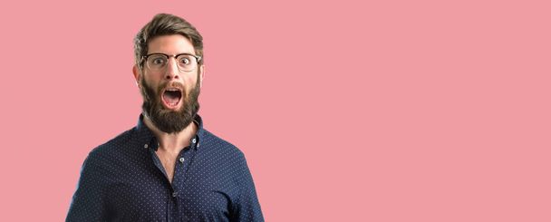 Young hipster man with big beard happy and surprised cheering expressing wow gesture - Photo, Image