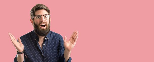 Jonge hipster man met grote baard blij en verrast juichen waarin wow gebaar - Foto, afbeelding
