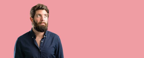 Young hipster man with big beard doubt expression, confuse and wonder concept, uncertain future - Photo, image