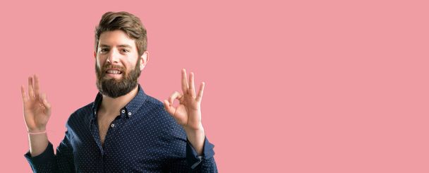 Young hipster man with big beard doing ok sign gesture with both hands expressing meditation and relaxation - Photo, Image