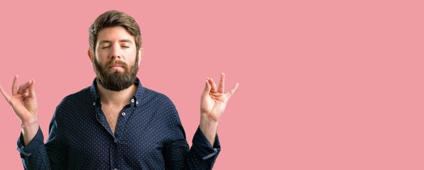 Jeune homme hipster avec une grosse barbe faisant signe ok geste avec les deux mains exprimant la méditation et la relaxation
 - Photo, image