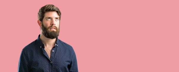 Jonge hipster man met grote baard maken grappige gezicht gek - Foto, afbeelding