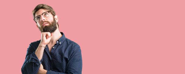 Düşünme ve şüphe ve merak ifade seyir büyük sakallı genç hipster adam - Fotoğraf, Görsel