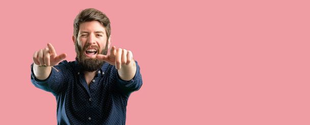 Homem jovem hipster com barba grande apontando para a frente com o dedo
 - Foto, Imagem