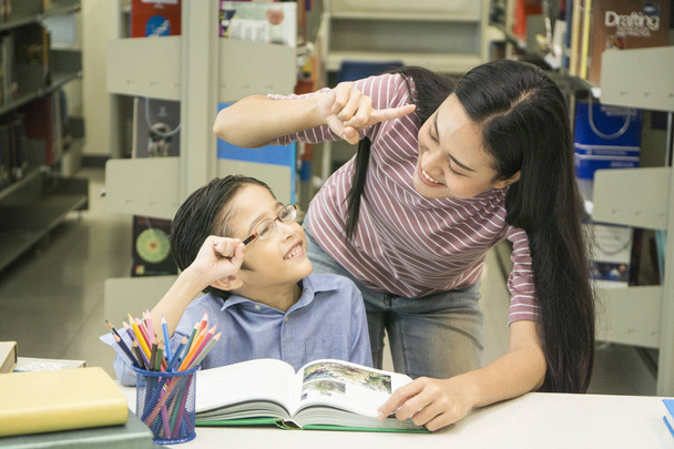 mujer profesor y niño estudiante aprender con libro en librería fondo
 - Foto, Imagen