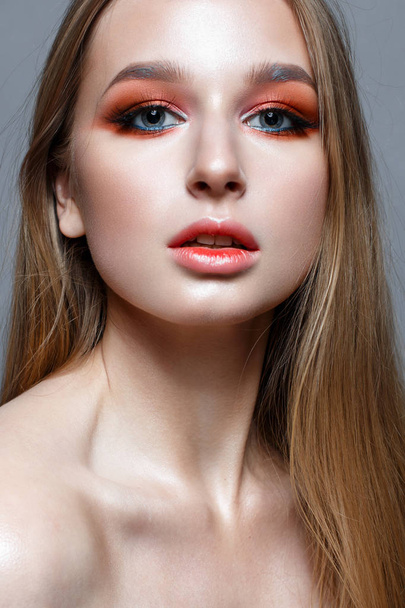 A young girl with long hair and bright creative make-up. Beautiful blond model with shining perfect skin. Beauty of the face. Photo is taken in the studio. - Photo, image