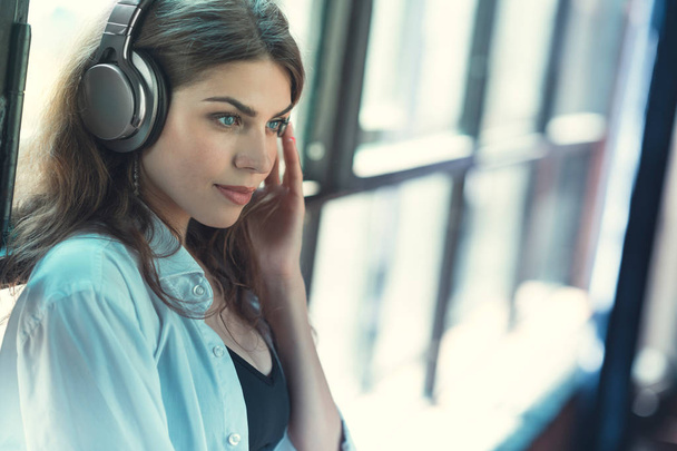 Young girl listening to music on headphones indoors - Valokuva, kuva