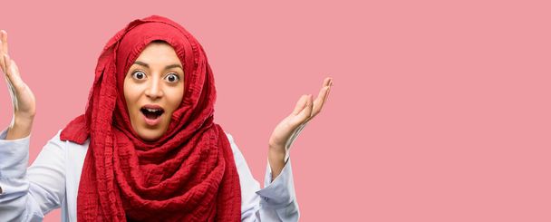 Young arab woman wearing hijab happy and surprised cheering expressing wow gesture - Photo, Image