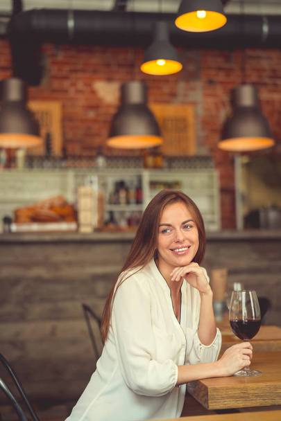 Lachende meisje met een glas rode wijn binnenshuis - Foto, afbeelding