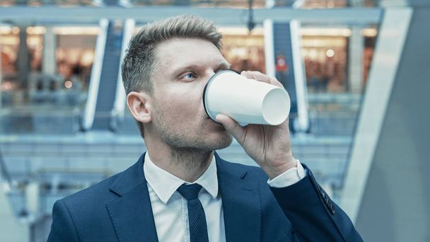 Молодой бизнесмен пьет кофе в магазине
 - Фото, изображение