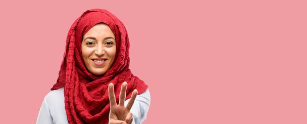 Młoda kobieta Arabska noszenie hidżabu podnoszenie jego palec jest numer trzy - Zdjęcie, obraz