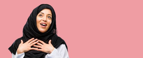 jovem árabe mulher vestindo hijab ter encantador sorriso de mãos dadas no coração querendo mostrar amor e simpatia
 - Foto, Imagem