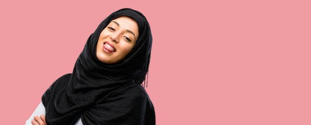 Jonge Arabische vrouw het dragen van hijab uitsteken van de tong op camera bij teken van ongehoorzaamheid, protest en gebrek aan respect - Foto, afbeelding
