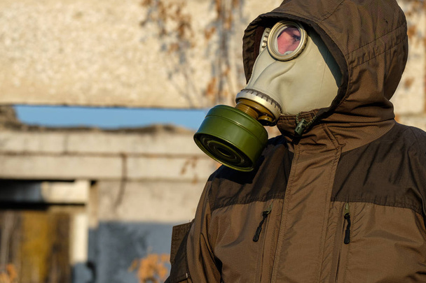 αξιολογεί τον κίνδυνο ενός άνδρα σε μια μάσκα αερίων, εξετάζοντας την απόσταση, πράσινη μάσκα αερίων και ίδιου χρώματος, φθινόπωρο - Φωτογραφία, εικόνα