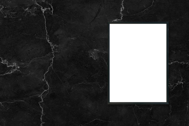 Образец пустой рамки плаката висит на черном мраморном фоне стены в помещении - может быть использован макет для монтажа продуктов отображения и дизайна ключевых визуальных макетов
. - Фото, изображение