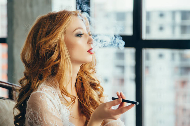 Attractive young woman smoking electronic cigarette. - 写真・画像