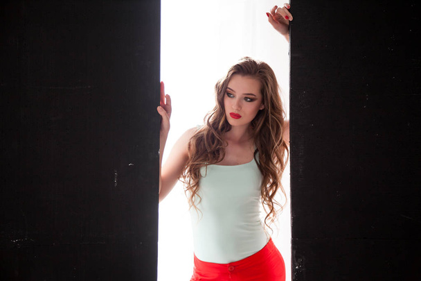 Portrait of fashionable girl in red pants on a black background - Photo, Image