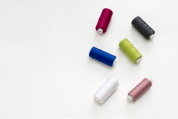 Colored thread coils on white background, sewing, place for text - Φωτογραφία, εικόνα