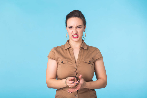 Злая агрессивная женщина с свирепым выражением лица на синем фоне
 - Фото, изображение
