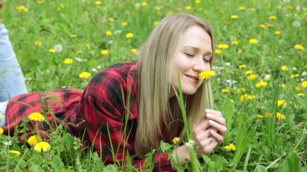 Young woman smelling a flower lying on a green grass. - Footage, Video