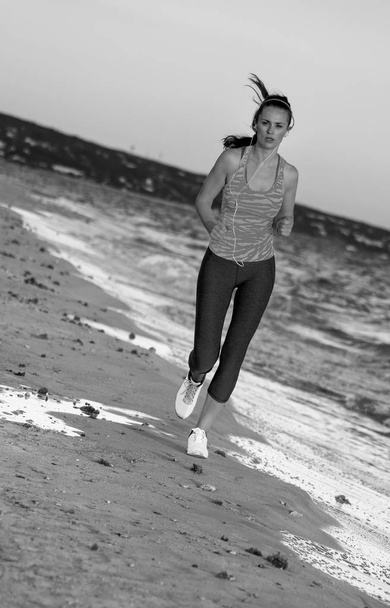 healthy fit woman in sport style clothes on the seashore in the evening running - Fotoğraf, Görsel