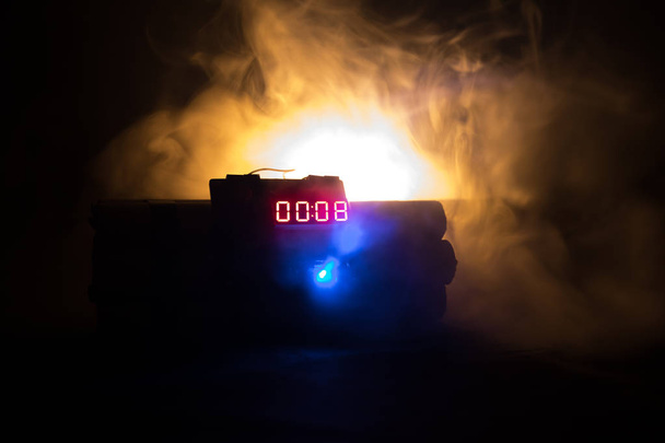 Εικόνα του μια ωρολογιακή βόμβα ενάντια σε σκούρο φόντο. Χρονόμετρο μετρά κάτω από εκπυρσοκρότηση φωτίζεται σε ένα άξονα φως που λάμπει μέσα από το σκοτάδι, εννοιολογική εικόνα - Φωτογραφία, εικόνα