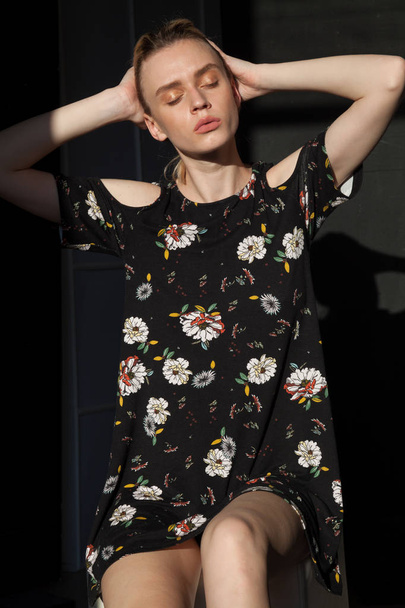 trendy blonde woman in black dress with flowers - Foto, afbeelding