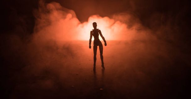Silhouet van een man die op een mistige donker getinte achtergrond. Versierde foto met man figuur op tafel met licht. - Foto, afbeelding