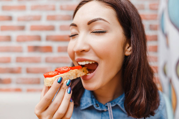 Joven mujer de belleza comiendo sándwich con verduras, concepto tradicional español de tapas snack
 - Foto, imagen