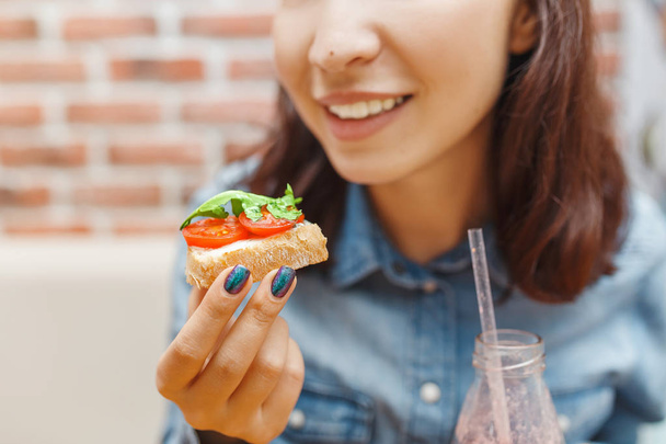 Young beauty woman eating sandwich with vegetables, spanish traditional tapas snack concept - Photo, Image