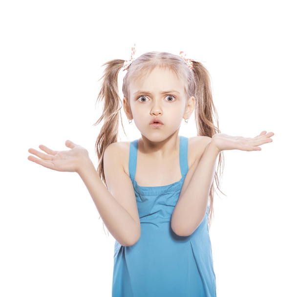Young seven years old brunette girl in blue dress on a white isolated background. Amazement, surprise emotions on her face - Zdjęcie, obraz