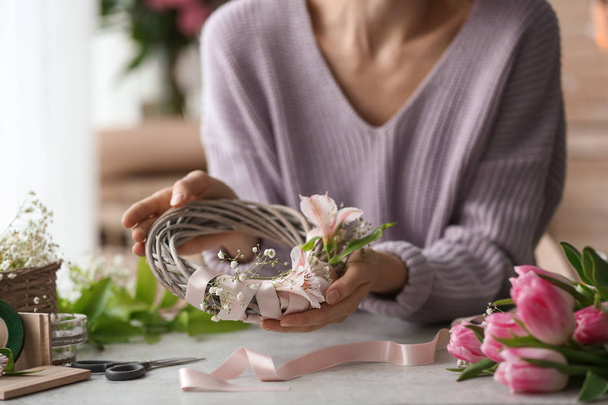 Female decorator creating beautiful wreath at table - Photo, Image
