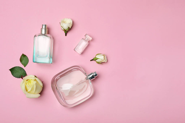 Bottles of perfume and roses on color background, top view - 写真・画像